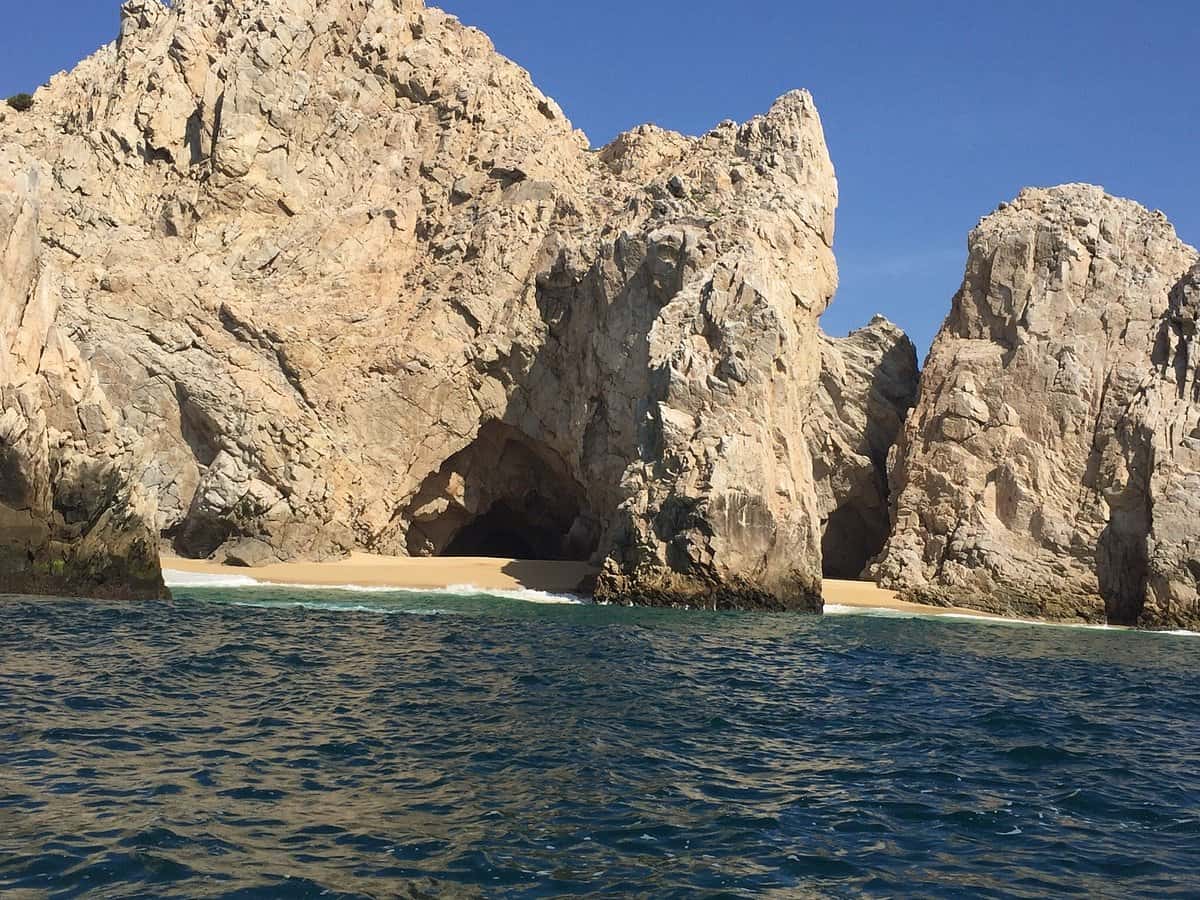 Granite cliffs and a small sandy cove at Land's End seen from a boat