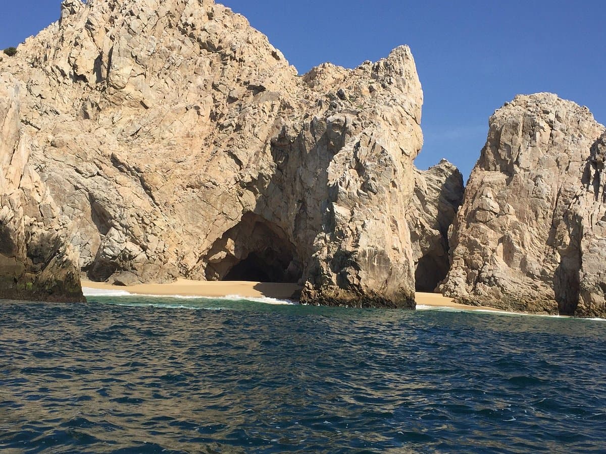 Granite cliffs and a small sandy cove at Land's End seen from a boat