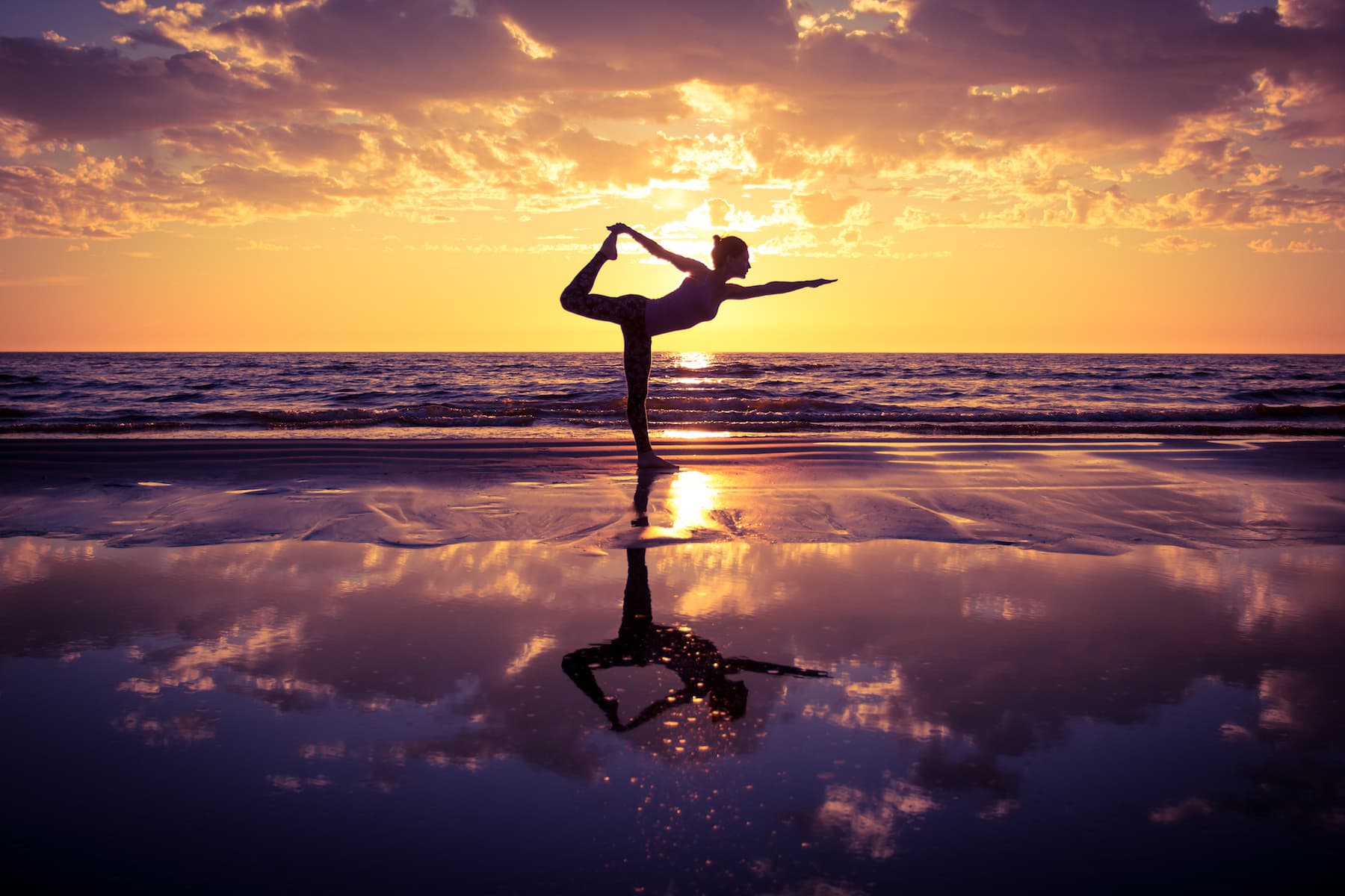 Yoga pose silhouetted against a sunset over the sea