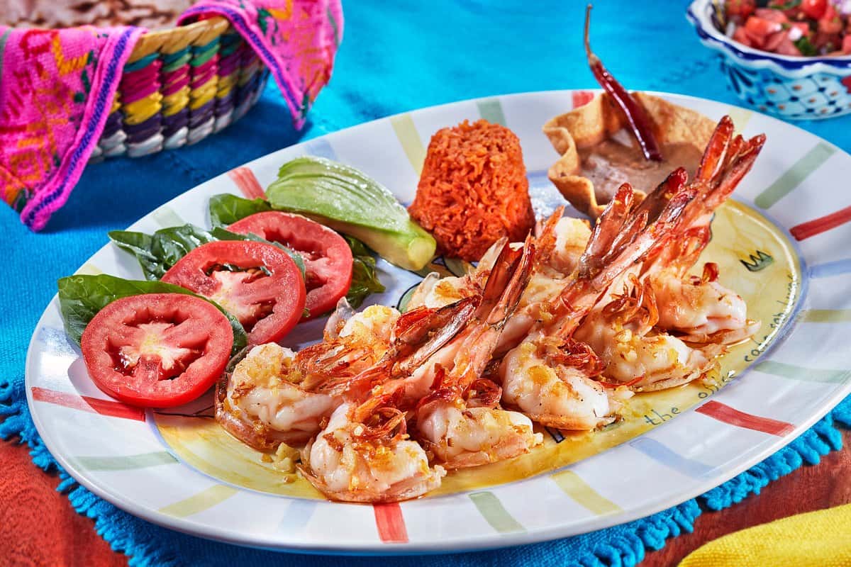Garlic shrimp with red rice, avocado and tomato on a painted plate at The Office on the Beach